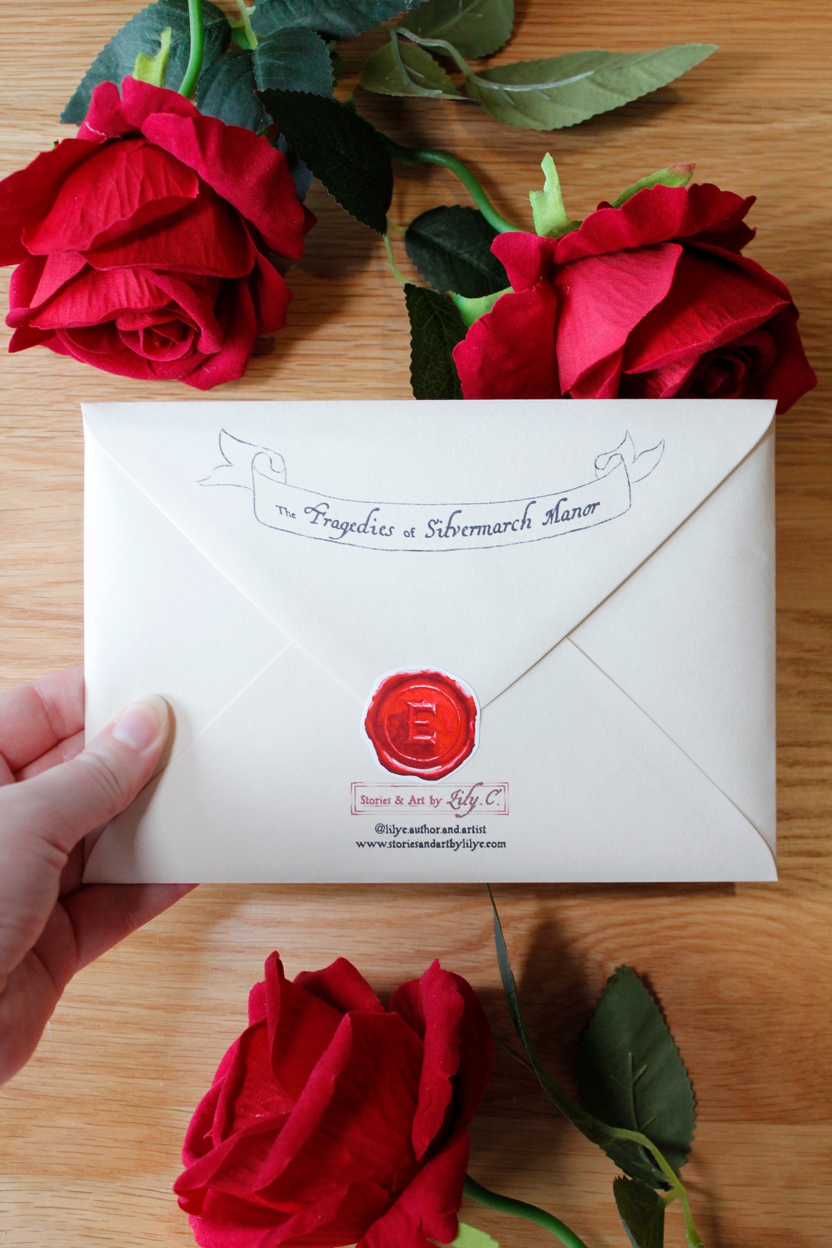 A hand holds a white envelope with a red wax seal and elegant script, set against a wooden background with red roses.